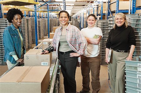 Team portrait of multi-ethnic female warehouse workers working next to a motorized feed conveyor in a large distribution warehouse. Stock Photo - Premium Royalty-Free, Code: 6118-09147870
