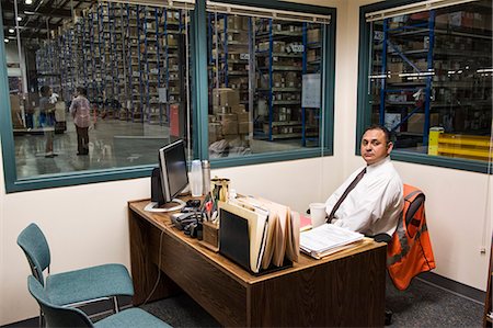 simsearch:6116-08915424,k - Portrait of a male Hispanic American executive  in an office in the middle of a large distribution warehouse full of racks of products stored in cardboard boxes on pallets. Foto de stock - Sin royalties Premium, Código: 6118-09147876