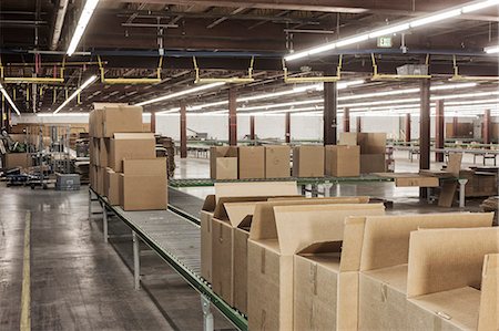 Interior view of a large distribution warehouse showing a motorized conveyor system to move products stored in cardboard boxes. Stock Photo - Premium Royalty-Free, Code: 6118-09147817