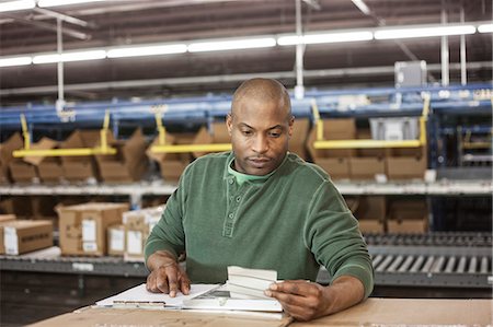 Working portrait of an African American warehouse worker in a large distribution warehouse. Stock Photo - Premium Royalty-Free, Code: 6118-09147818