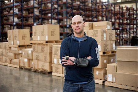 Portrait of a Caucasian warehouse worker in a large distribution warehouse, showing products stored in cardboard boxes. Stock Photo - Premium Royalty-Free, Code: 6118-09147837