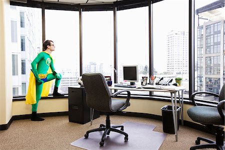 simsearch:6118-09148024,k - A Caucasian man office super hero stands at his office window pondering his next business move. Foto de stock - Sin royalties Premium, Código: 6118-09147992