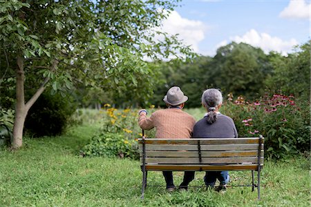 simsearch:700-05973994,k - Husband and wife, rear view of elderly man wearing hat and woman sitting side by side on a bench in a garden. Photographie de stock - Premium Libres de Droits, Code: 6118-09147926