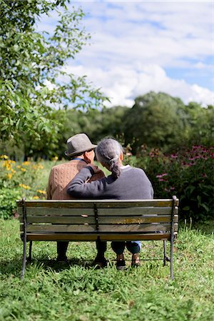 simsearch:700-05973994,k - Husband and wife, rear view of elderly man wearing hat and woman sitting side by side on a bench in a garden. Photographie de stock - Premium Libres de Droits, Code: 6118-09147929