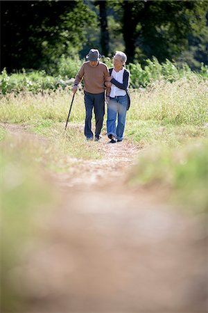 simsearch:700-05973994,k - Husband and wife, elderly man wearing hat and using walking stick and elderly woman walking along path. Photographie de stock - Premium Libres de Droits, Code: 6118-09147934