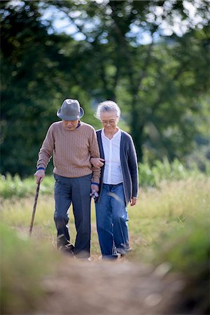 simsearch:700-05973994,k - Husband and wife, elderly man wearing hat and using walking stick and elderly woman walking along path. Photographie de stock - Premium Libres de Droits, Code: 6118-09147935