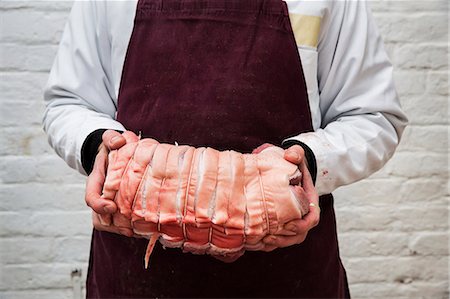 simsearch:6118-08729219,k - Close up of butcher wearing apron holding large rolled pork belly. Foto de stock - Sin royalties Premium, Código: 6118-09148169
