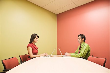 Hispanic man and Caucasian woman on lap top computers in a colourful  office conference room. Stock Photo - Premium Royalty-Free, Code: 6118-09148102