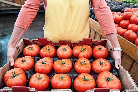 High angle close up of person holding large tray of fresh tomatoes at a fruit and vegetable market. Stock Photo - Premium Royalty-Free, Code: 6118-09148132