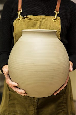 simsearch:6118-09059818,k - Close up of potter wearing apron holding unfired spherical clay vase. Stock Photo - Premium Royalty-Free, Code: 6118-09148244