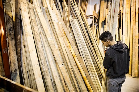 simsearch:6118-07121806,k - Young man standing next to a stack of wooden planks in a warehouse. Stockbilder - Premium RF Lizenzfrei, Bildnummer: 6118-09148251