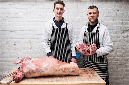 simsearch:6118-08729219,k - Two young men working, butchers jointing a whole lamb carcass. Foto de stock - Sin royalties Premium, Código: 6118-09165870