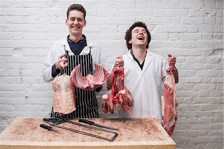 simsearch:6118-08729219,k - Two butchers at work holding up the butchered carcass of a spring lamp, ribs, shoulders, leg and rump. Foto de stock - Sin royalties Premium, Código: 6118-09165874