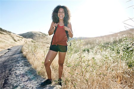 simsearch:6118-09165967,k - Young woman with curly brown hair hiking in urban park. Foto de stock - Sin royalties Premium, Código: 6118-09165943