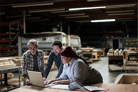 simsearch:6118-08088600,k - Three mixed race carpenters working on a laptop computer after work hours in a large woodworking factory. Photographie de stock - Premium Libres de Droits, Code: 6118-09165984