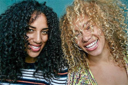 simsearch:6118-09165914,k - Portrait of two young women with long curly black and blond hair, smiling at camera. Foto de stock - Royalty Free Premium, Número: 6118-09165928