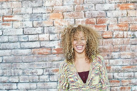 district - Portrait of young smiling woman with long curly blond hair, looking at camera. Stock Photo - Premium Royalty-Free, Code: 6118-09165934