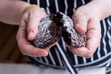 simsearch:649-09276212,k - A cook in an apron holding a dark chocolate brownie cake broken in half Foto de stock - Sin royalties Premium, Código: 6118-09166088