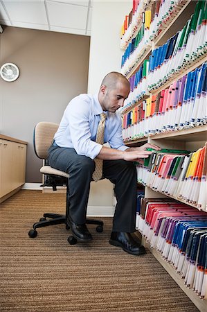 patient record - A Middle Eastern businessman looking through file folders, searching through paperwork for information. Stock Photo - Premium Royalty-Free, Code: 6118-09166148
