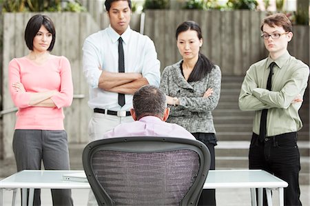 simsearch:6118-09139994,k - A mixed race group of business people standing in front of a person at a desk. Foto de stock - Sin royalties Premium, Código: 6118-09166211