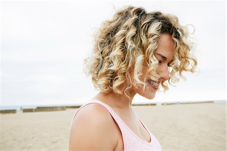 redondo beach - Portrait of smiling young woman with blond curly hair standing on sandy beach. Photographie de stock - Premium Libres de Droits, Code: 6118-09166302