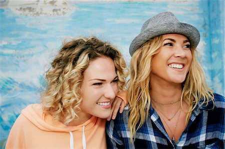 sorriso - Portrait of two smiling women with blond hair wearing pink hoodie, blue checked shirt and grey Trilby hat. Fotografie stock - Premium Royalty-Free, Codice: 6118-09166315