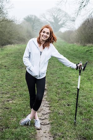 simsearch:6118-09165967,k - Young woman with long red hair wearing sports kit, exercising outdoors, looking at camera. Foto de stock - Sin royalties Premium, Código: 6118-09173441