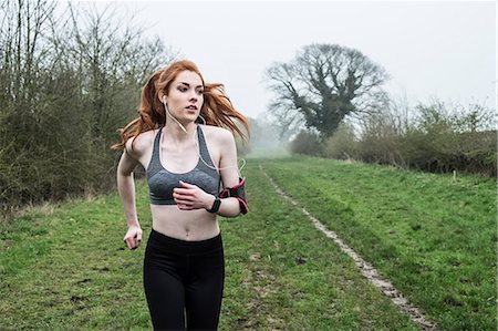 simsearch:6118-09165967,k - Young woman with long red hair wearing sports kit, exercising outdoors. Foto de stock - Sin royalties Premium, Código: 6118-09173437