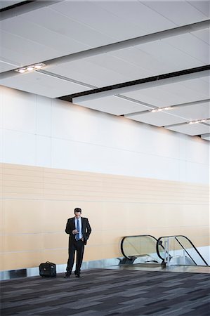 simsearch:632-03847867,k - Caucasian businessman checking his cell phone in a conference centre lobby. Stock Photo - Premium Royalty-Free, Code: 6118-09173550