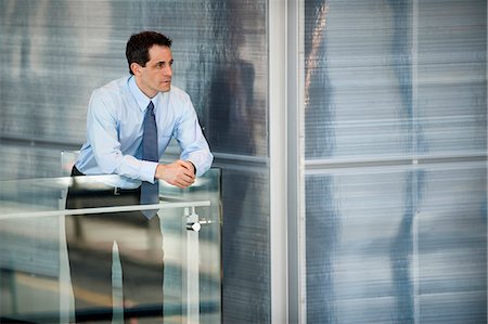 simsearch:6118-09173924,k - Businessman standing at a railing in a conference centre lobby. Stockbilder - Premium RF Lizenzfrei, Bildnummer: 6118-09173559