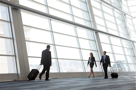 simsearch:693-06379884,k - Three business people walking next to a large window in a conference centre lobby. Stock Photo - Premium Royalty-Free, Code: 6118-09173568