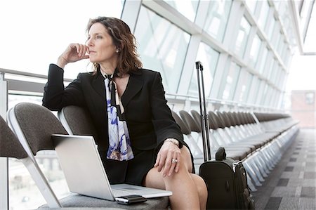 simsearch:6118-09173926,k - Caucasian businesswoman sitting in a row of chairs against a window in a conference centre lobby. Stock Photo - Premium Royalty-Free, Code: 6118-09173572