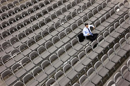 simsearch:6118-09173924,k - View from above looking down on a businessman sitting alone in a room full of chairs prior to meeting in a conference centre. Stockbilder - Premium RF Lizenzfrei, Bildnummer: 6118-09173574