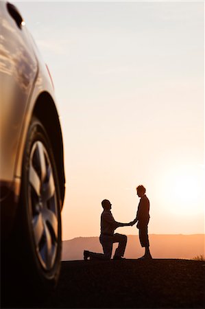 Senior man proposing to a woman while watching a sunset on a road trip. Stock Photo - Premium Royalty-Free, Code: 6118-09173644