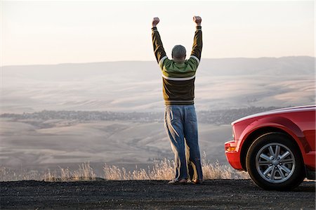 simsearch:6118-08488428,k - Caucasian male celebrating with his arms n the air standing next to his car at a rest stop near Lewiston, Idaho USA. Stock Photo - Premium Royalty-Free, Code: 6118-09173653