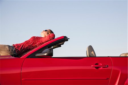 simsearch:6118-08488428,k - A Caucasian woman resting on the hood of her convertible sports car at a rest stop. Stock Photo - Premium Royalty-Free, Code: 6118-09173681