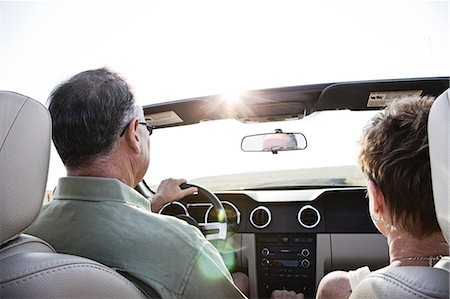 View from behind of senior couple in a convertible sports car driving on a highway at sunset in eastern Washington State, USA. Stock Photo - Premium Royalty-Free, Code: 6118-09173634
