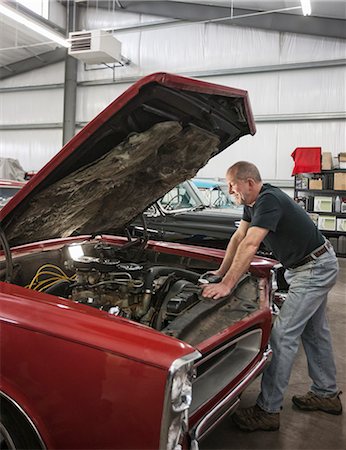 A senior car mechanic working on a car in his repair shop. Stock Photo - Premium Royalty-Free, Code: 6118-09173991