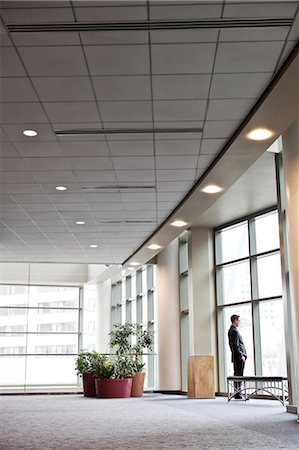 simsearch:6118-09173926,k - A businessman standing at a window in a large convention centre lobby. Stock Photo - Premium Royalty-Free, Code: 6118-09173918