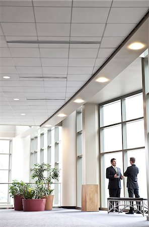 simsearch:6118-09173926,k - Two businessmen meeting in front of a window in a large convention centre lobby. Stock Photo - Premium Royalty-Free, Code: 6118-09173919