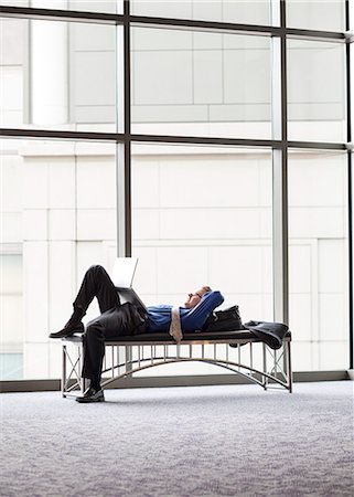 simsearch:6118-09173926,k - A businessman working on a laptop computer on a bench in a convention centre lobby Stock Photo - Premium Royalty-Free, Code: 6118-09173920