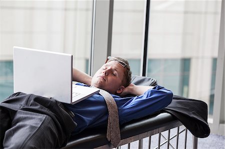 simsearch:6118-09173926,k - A businessman working on a laptop computer on a bench in a convention centre lobby Stock Photo - Premium Royalty-Free, Code: 6118-09173922