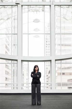 simsearch:6118-09173926,k - A portrait of a young businesswoman standing in front of a window in a large convention centre lobby. Stock Photo - Premium Royalty-Free, Code: 6118-09173926