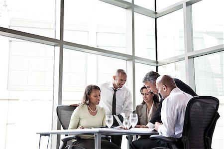 simsearch:6118-09173926,k - A mixed race group of male and female business people in a meeting at a conference table next to a large window in a convention centre. Stock Photo - Premium Royalty-Free, Code: 6118-09174099