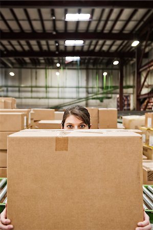simsearch:6118-09174220,k - A Caucasian female warehouse worker behind a cardboard box in a distribution warehouse. Fotografie stock - Premium Royalty-Free, Codice: 6118-09174176
