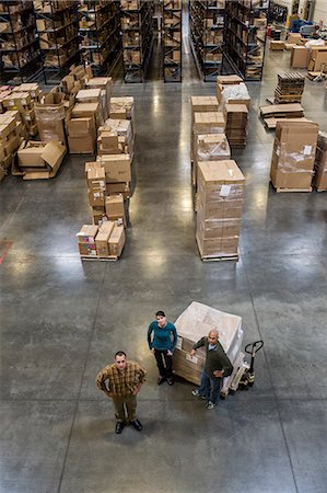 A group of three warehouse workers standing in the centre of a distribution warehouse. Stock Photo - Premium Royalty-Free, Code: 6118-09174186