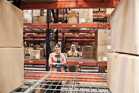 simsearch:6118-09174185,k - A Caucasian male and female warehouse workers surrounded by boxed products on racks in a distribution warehouse. Stockbilder - Premium RF Lizenzfrei, Bildnummer: 6118-09174188