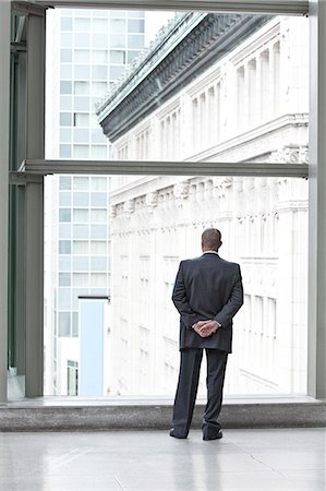 simsearch:6118-09173924,k - A businessman standing at a convention centre window looking out the window at the city in the background. Stockbilder - Premium RF Lizenzfrei, Bildnummer: 6118-09174118