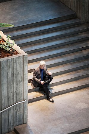 simsearch:6118-09174347,k - Businessman working on a notebook computer while sitting on the steps of a convention centre. Fotografie stock - Premium Royalty-Free, Codice: 6118-09174243