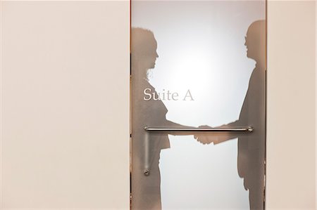 simsearch:625-01040683,k - Two business people shaking hands and silhouetted through the frosted glass door of an office suite Photographie de stock - Premium Libres de Droits, Code: 6118-09174246
